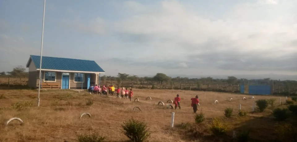 Learners walking across the grounds towards a blue-roofed school building